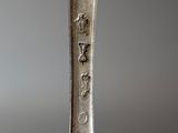 a silver spoon with writing on it sitting on a table