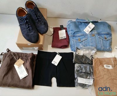 Plusieurs paires de pantalons et de chaussures pour homme sont disposées sur une table