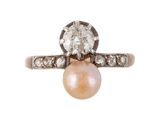 un gros plan d'une bague sertie d'un diamant et d'une perle sur fond blanc