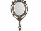 an ornate mirror with a long handle hanging on a wall