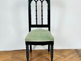 a black chair with a green seat sitting on top of a wooden floor