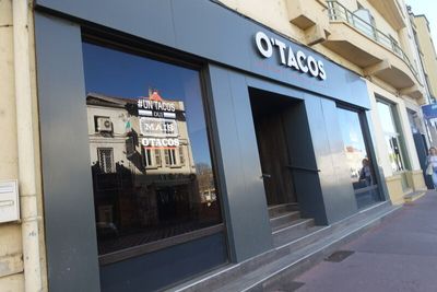 le reflet d'un immeuble dans la vitrine d'un restaurant de tacos