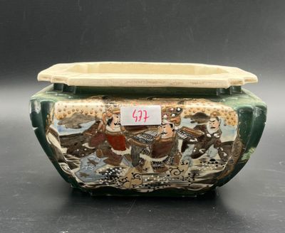 a green vase with a picture on it on a table