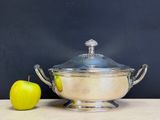 a silver bowl and an apple on a table