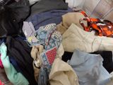 a pile of clothes sitting on a bed next to a suitcase