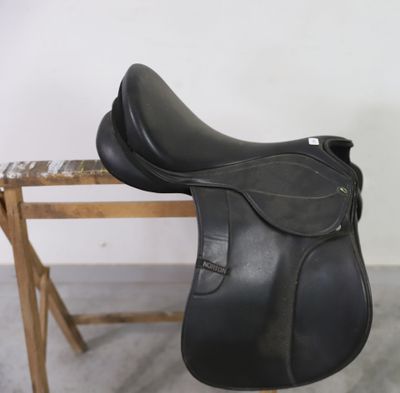 un gros plan d'une selle noire posée sur un banc en bois