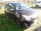 a small black car parked in the grass next to a fence