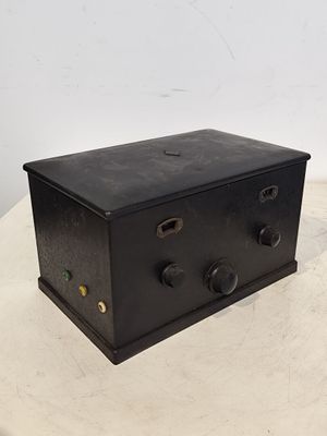 une vieille boîte en métal noir posée sur une table blanche