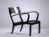 une chaise noire posée sur un sol blanc, près d'un mur