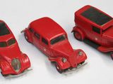 trois petites voitures rouges posées les unes à côté des autres sur une surface blanche