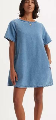 une femme en robe bleue se tient debout devant un fond blanc
