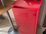 a red locker next to a table with a hat on it