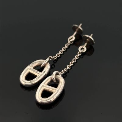 une paire de boucles d'oreilles en argent posées sur une surface noire