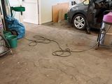 une voiture garée dans un garage, avec un aspirateur posé par terre