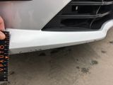 someone is measuring the front bumper of a car with a tape