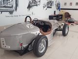 a silver race car sitting in a room with pictures on the wall