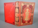 an old book with a red cover sitting on top of a table