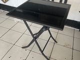 une table noire avec un plateau en verre, posée sur un sol carrelé