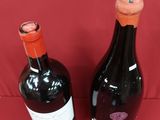 two bottles of wine sitting next to each other on a red surface