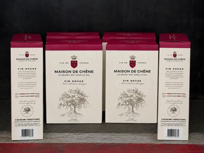 trois cartons de vin posés sur une étagère devant un mur noir