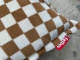 un coussin à carreaux marron et blancs posé par terre