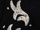 a black jacket with silver sequins and a bird on it