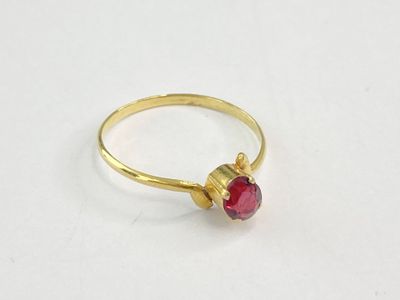 gros plan d'une bague en or avec une pierre rouge