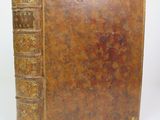an old book with a brown cover sitting on top of a table