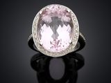 an oval pink sapphire and diamond ring on a black surface