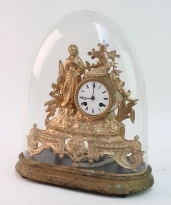 une horloge en or sous un dôme de verre sur une table
