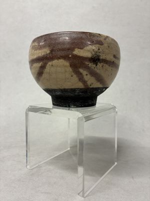 un petit bol posé sur un socle transparent, sur une surface blanche