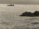 a boat that is out in the water near some rocks