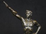 bronze statue of a man holding a tennis racquet in his right hand