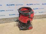 a red and black vacuum cleaner sitting on the ground next to a wall