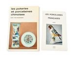 two books on a white table with a bird and a vase