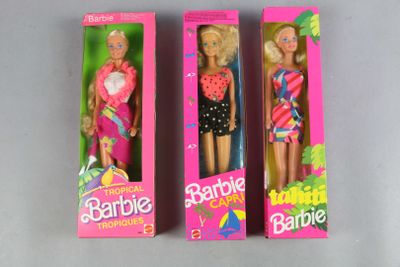 three barbie dolls are in a pink box on a gray surface