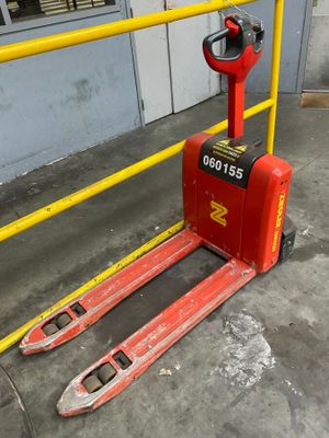 a red fork lift truck parked in front of a building