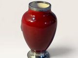 a red vase with a silver lid sitting on a white surface