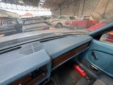 dashboard of a car in a garage with several cars in the background
