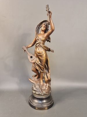 statue en bronze d'une femme tenant un oiseau sur un piédestal