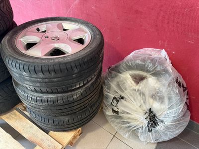 des pneus posés sur une palette, près d'un mur rose et d'un sac en plastique