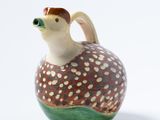 un petit vase avec un oiseau sur une surface blanche