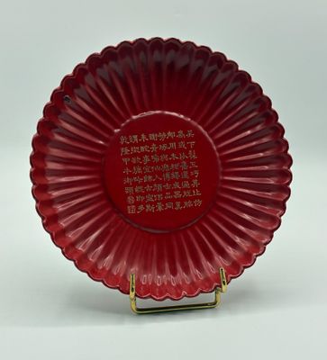 assiette en verre rouge ornée d'inscriptions en chinois, posée sur un socle doré
