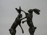 statue of two rabbits fighting each other on a marble base