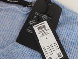a close up of a blue sweater with a tag on it