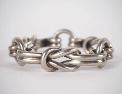 a close up of a silver bracelet on a white surface