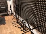 several microphone stands are lined up against a wall in a recording studio