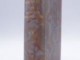 un vieux livre posé sur une table blanche à côté d'un mur blanc