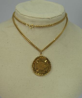 a gold necklace with a coin on a mannequin neck