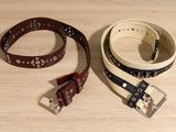 two belts that are sitting on a wooden table